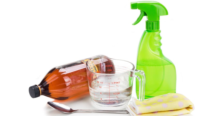 Natural window cleaner ingredients, including water, white vinegar, and cornstarch in a spray bottle, with a soft cloth.